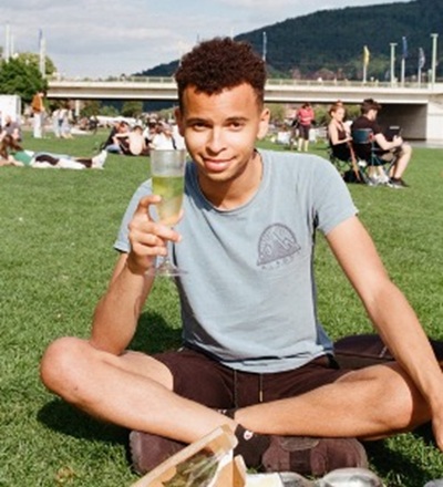 Dayon Ketchens holds up a glass of champagne while sitting in the grass.
