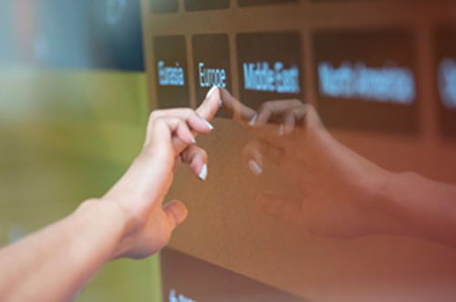 A hand pressing "Europe" on a touchscreen sign