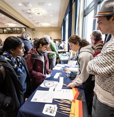 German students standing at a table at a language fair.
